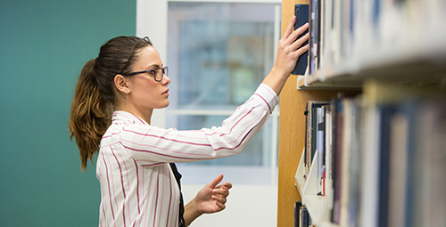 Student taking book off shelf