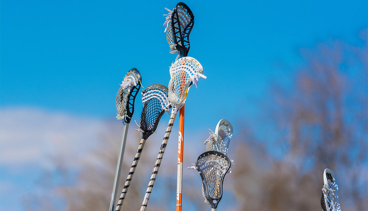 Lacrosse sticks being held in the air.