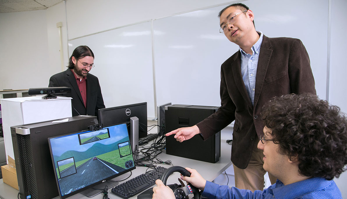 Faculty and students using the driving simulator.