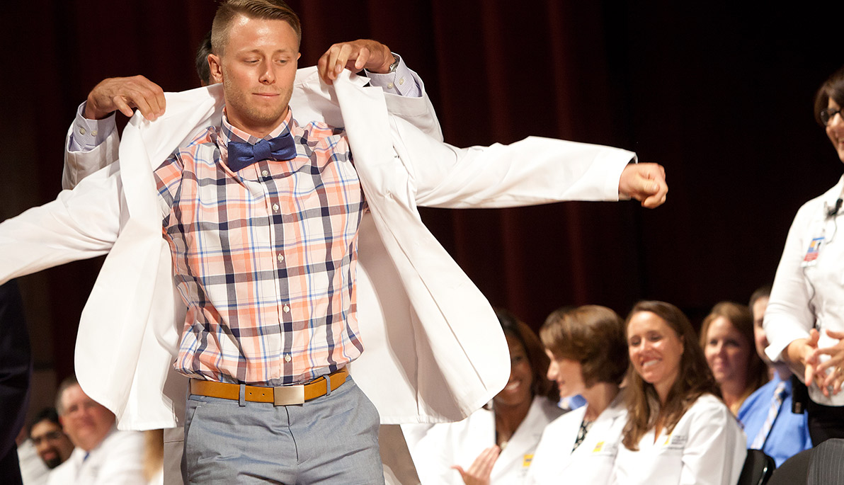 NYITCOM student receiving his white coat.