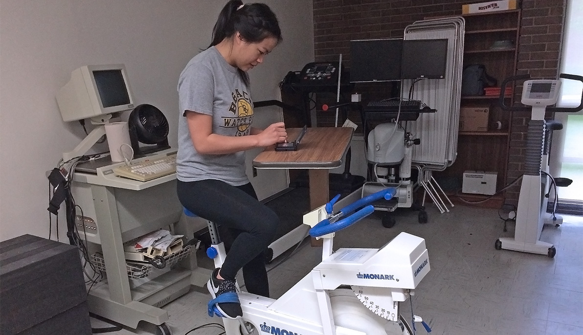 NYIT student on a stationary bicycle and playing a video game.