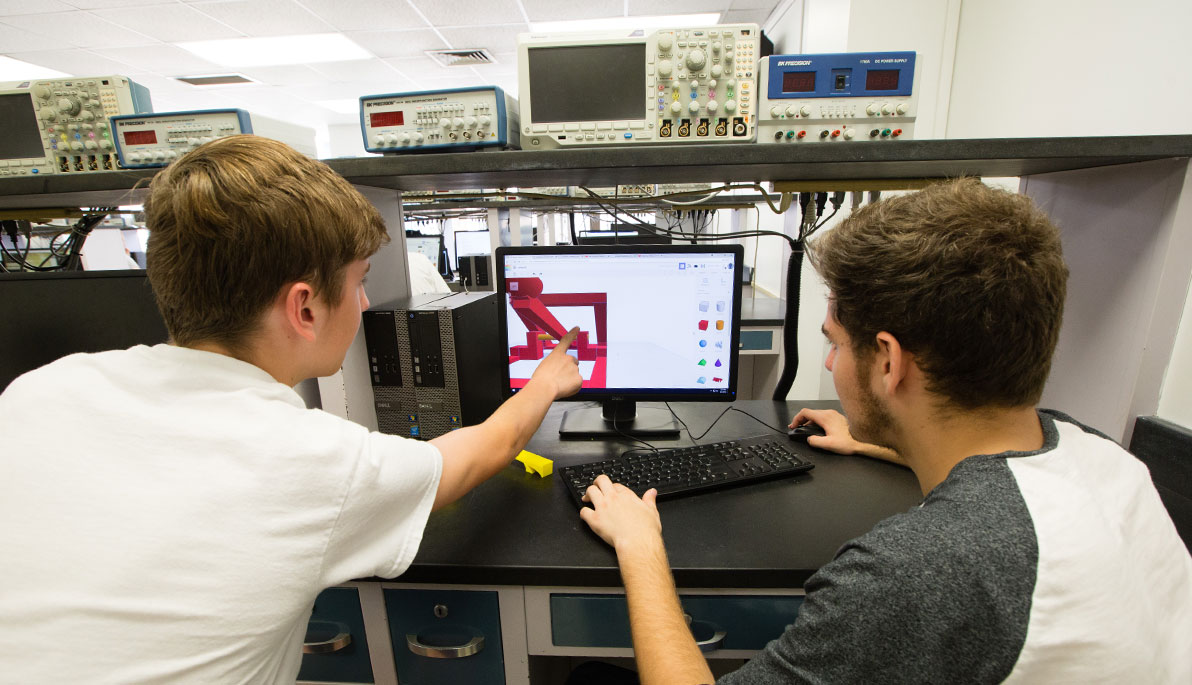 Two high school students looking at a computer screen.