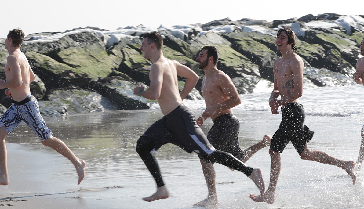 NYIT student-athletes running into the ocean.