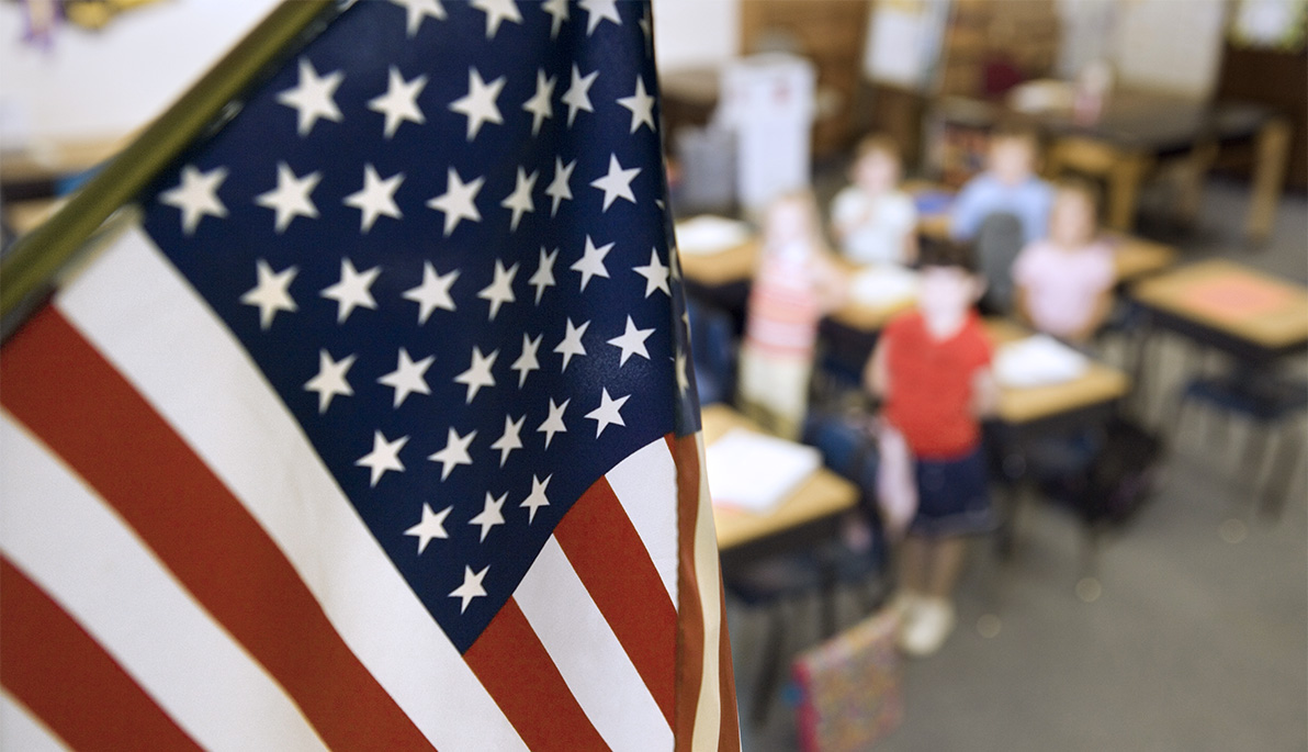 American flag with elementary school student in background