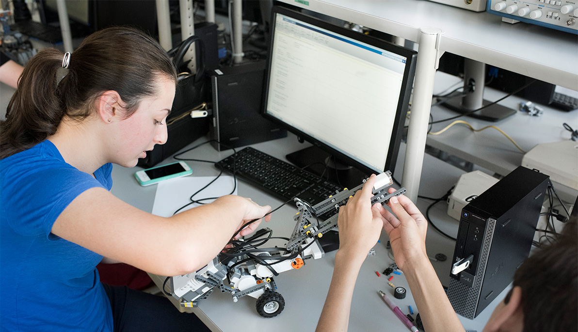 A young high school student works on a robotic arm. A young high school student works on a robotic arm.