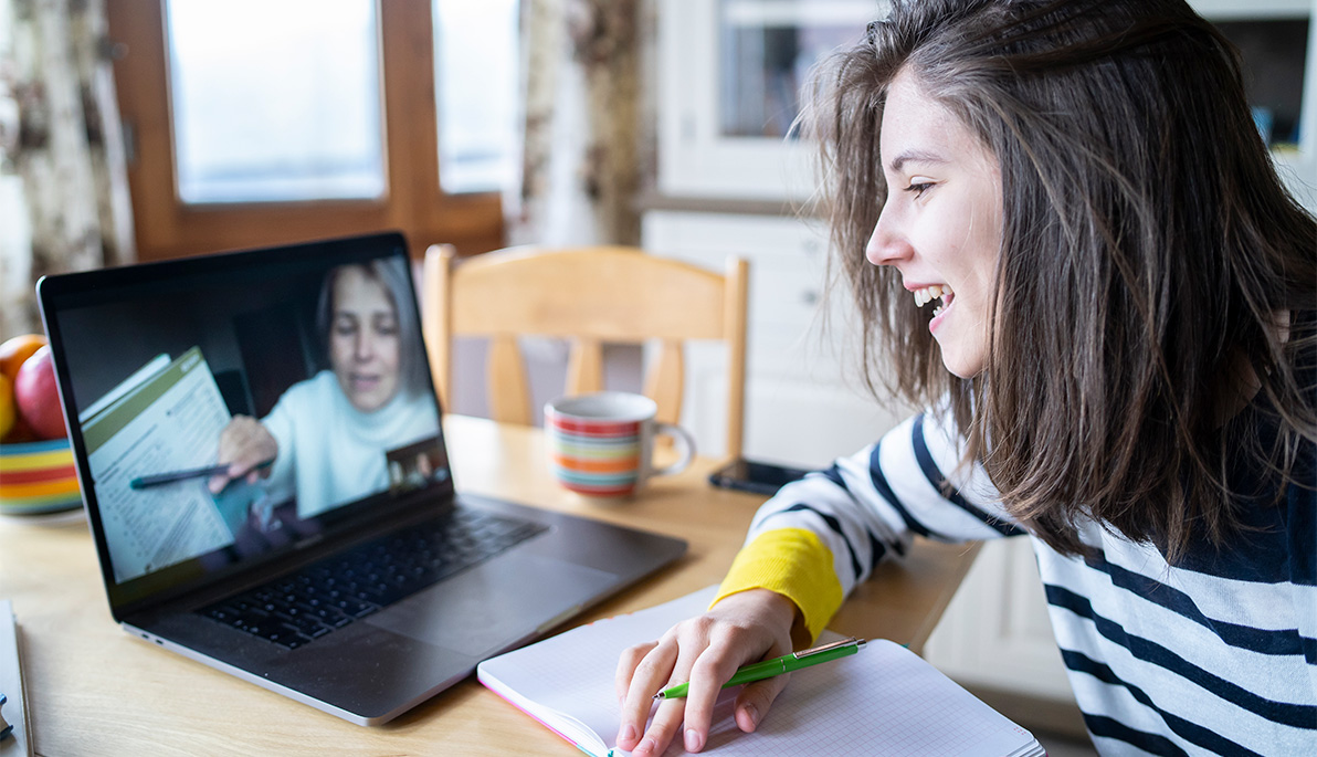 Young woman with her laptop taking an online course at her kitchen table