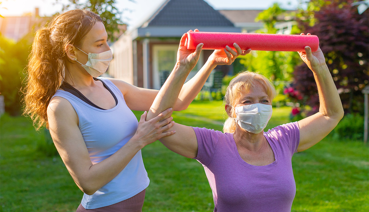 Young woman helping another woman exercise.