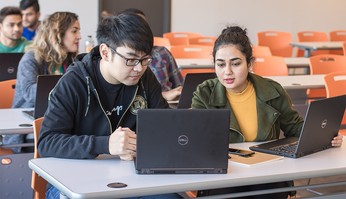 Tw students looking at a laptop.