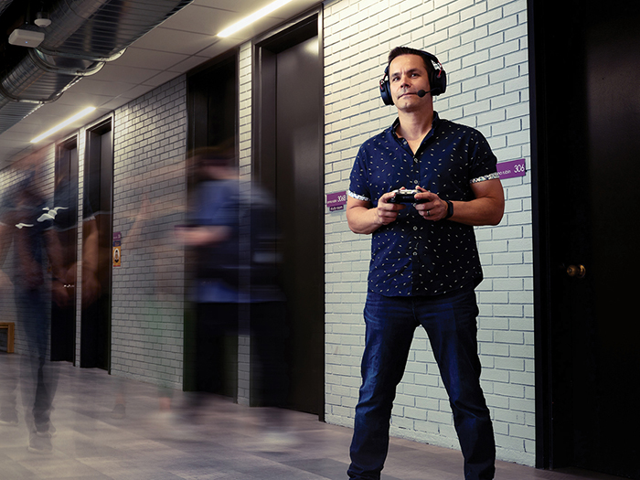 John Misak standing in hallway holding controller