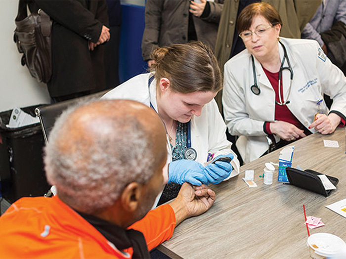 Associate Professor Sonia Rivera-Martinez, D.O., looks on as Bill Perkins, New York City Council, District 9 (left), volunteers for a wellness screening.