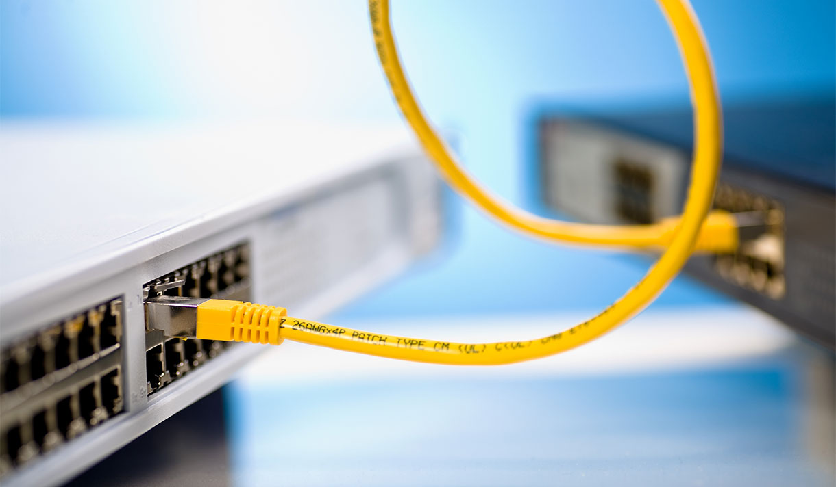 Abstract close-up of curling yellow USB cable connecting two computers.