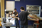 NYIT architecture students Kevin Kaweicki and Chris Cetola drill holes into a wooden slat.