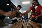 NYIT architecture students Jimmy Carbajal and Stephanie Ramanand stain wood.