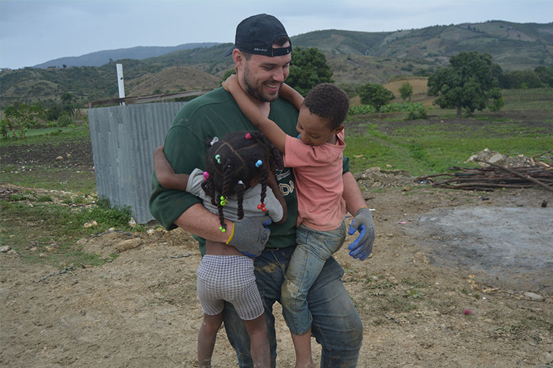 Student Robby O’Malley takes a break to have some fun with two local children.