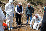 Carefully digging through the dirt to find the buried body.