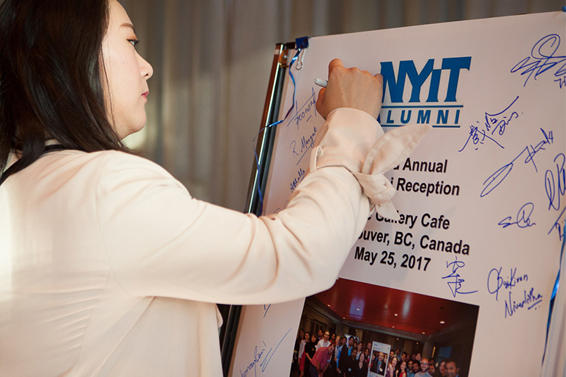 Writing a message of congratulations at the alumni luncheon.