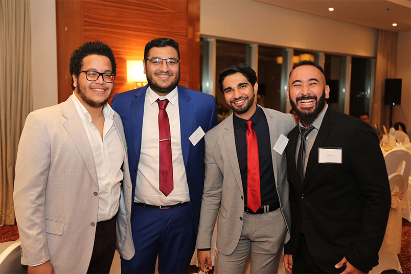 Speakers Haji Arif (second from left) and Nassir Etout (far right), smile for the camera with fellow alumni.