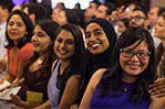 A group of female students wait to receive their coats.