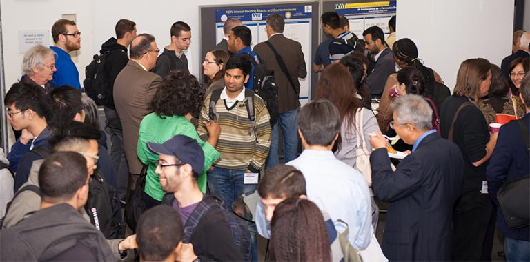 Cyber security conference participants view research posters.